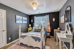 Bedroom featuring carpet floors, a textured ceiling, a ceiling fan, and visible vents