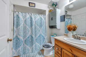 Bathroom with curtained shower, visible vents, toilet, vanity, and a textured ceiling