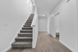 Stairs with baseboards, wood finished floors, and recessed lighting