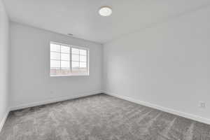 Carpeted spare room featuring baseboards and visible vents