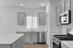 Kitchen with light countertops, appliances with stainless steel finishes, gray cabinetry, and a sink