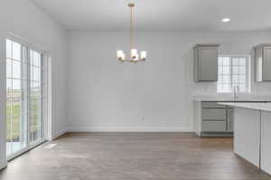 Kitchen featuring baseboards, a chandelier, light wood-style floors, and gray cabinets