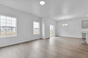 Unfurnished living room with baseboards, light wood-style floors, and a notable chandelier
