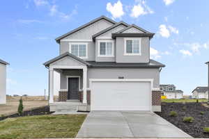 Craftsman-style house with concrete driveway, brick siding, an attached garage, board and batten siding, and stucco siding
