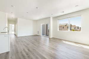 Unfurnished living room featuring baseboards, light wood-style flooring, visible vents, and a textured ceiling