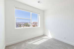 Spare room featuring carpet floors, visible vents, and baseboards