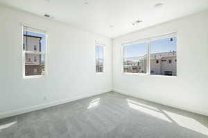 Carpeted spare room with visible vents and baseboards