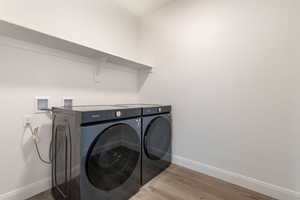 Laundry area featuring washing machine and dryer, baseboards, wood finished floors, and laundry area