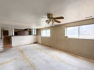 Unfurnished room with a textured ceiling, stairway, visible vents, and ceiling fan