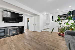 Living area with recessed lighting, stairway, wood finished floors, baseboards, and a fireplace