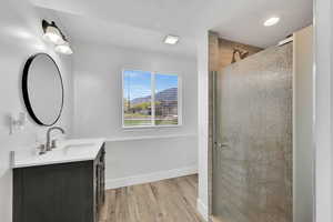 Bathroom with a shower stall, wood finished floors, vanity, baseboards, and recessed lighting