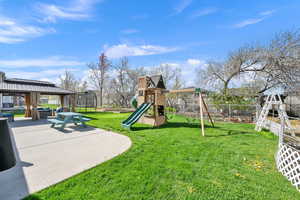 View of yard featuring a trampoline, a gazebo, playground community, and fence