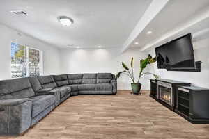 Living room featuring a textured ceiling, visible vents, recessed lighting, and light wood-style floors