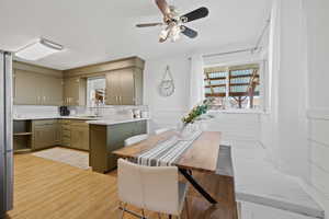 Kitchen with a sink, light wood-type flooring, ceiling fan, light countertops, and a peninsula