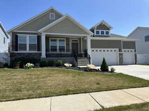 Craftsman house featuring a garage, stone siding, a front lawn, and concrete driveway