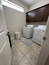 Washroom featuring cabinet space, baseboards, light tile patterned floors, and separate washer and dryer