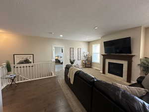 Living room featuring a textured ceiling, baseboards, recessed lighting, wood finished floors, and a fireplace