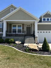 Craftsman house featuring a front lawn, a porch, and a garage