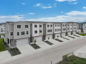 View of property featuring an attached garage, fence, a residential view, and driveway