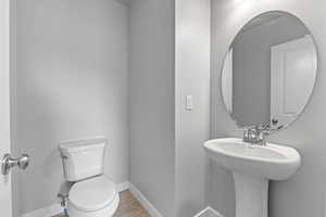 Bathroom with wood finished floors, baseboards, a sink, and toilet