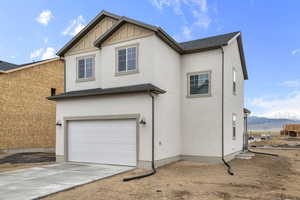 View of front of home with stucco siding, an attached garage, a mountain view, and concrete driveway