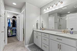 Bathroom with a spacious closet, a sink, a shower stall, and double vanity
