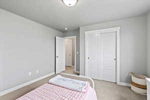 Bedroom with baseboards, a closet, and light colored carpet