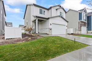 View of front of property with fence, stone siding, driveway, and a front yard