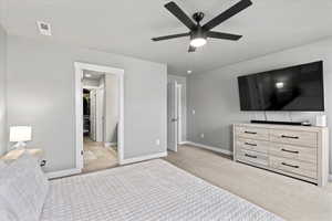 Bedroom with a spacious closet, ceiling fan, carpet floors, baseboards, and visible vents
