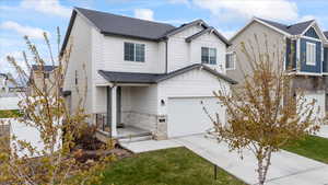 View of front of home with concrete driveway, stone siding, board and batten siding, a garage, and roof with shingles