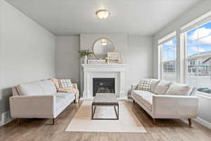 Living room with hardwood / wood-style flooring, baseboards, a glass covered fireplace, and visible vents