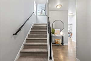 Stairway with wood finished floors, a textured ceiling, and baseboards