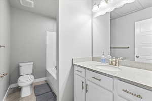 Full bathroom with visible vents, toilet, vanity, baseboards, and a tub