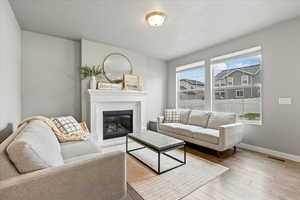 Living room featuring baseboards, a glass covered fireplace, and hardwood / wood-style floors