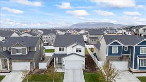 View of front of property featuring a mountain view, a residential view, and driveway