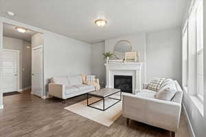 Living area featuring baseboards, a glass covered fireplace, and wood finished floors