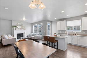 Kitchen featuring wood finished floors, a sink, a kitchen island, open floor plan, and white cabinetry