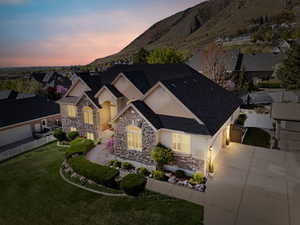View of front of property featuring fence, concrete driveway, stucco siding, stone siding, and a mountain view