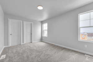 Unfurnished bedroom with baseboards, visible vents, and carpet floors