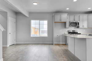 Kitchen featuring stainless steel appliances, light countertops, baseboards, and recessed lighting