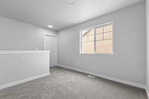 Empty room featuring carpet, visible vents, and baseboards