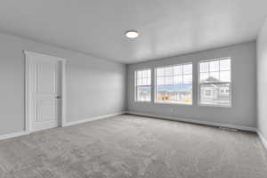 Carpeted empty room featuring baseboards and visible vents