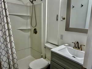 Full bathroom featuring a shower stall, toilet, and vanity