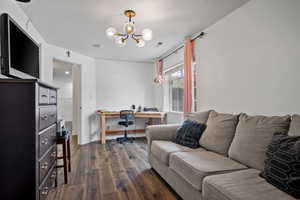 Office space featuring baseboards, visible vents, a chandelier, and dark wood finished floors