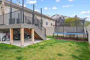 View of yard featuring stairs, fence, a patio area, a mountain view, and a trampoline