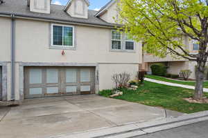 Exterior space featuring a yard, an attached garage, stucco siding, and driveway