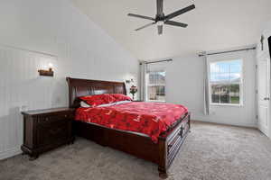 Carpeted bedroom with a ceiling fan and high vaulted ceiling