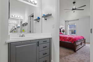 Ensuite bathroom featuring vaulted ceiling, ensuite bath, a ceiling fan, and vanity
