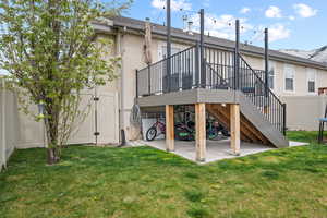 Back of house featuring a patio area, a lawn, fence, stucco siding, and stairs