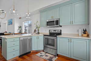 Kitchen featuring dark wood finished floors, a peninsula, appliances with stainless steel finishes, and a sink